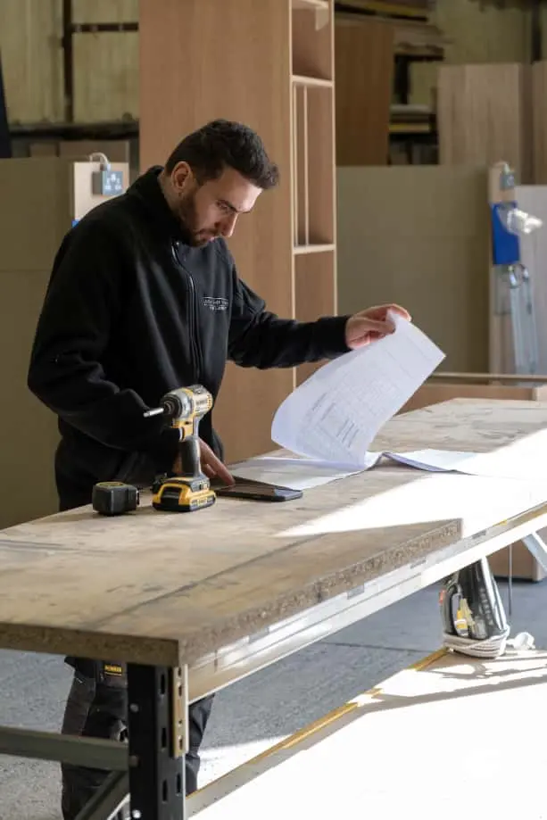 A craftsman meticulously finishing a piece of wooden cabinetry.